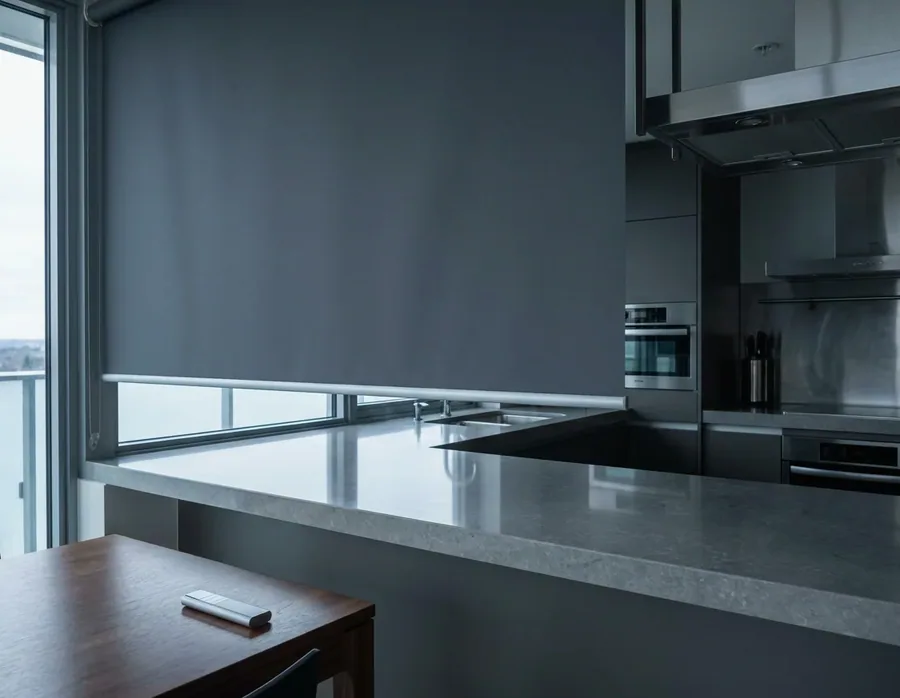 Motorised roller blind lowered over a kitchen window, its handheld remote lying on the table
