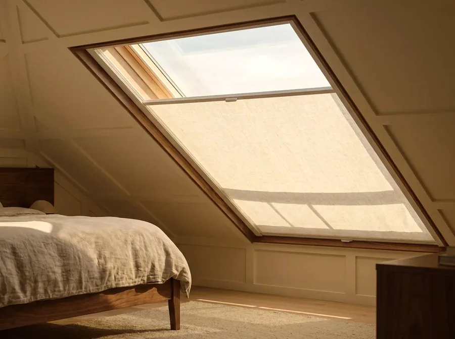 Blind fitted to a sloped skylight in a loft bedroom, guided in side channels